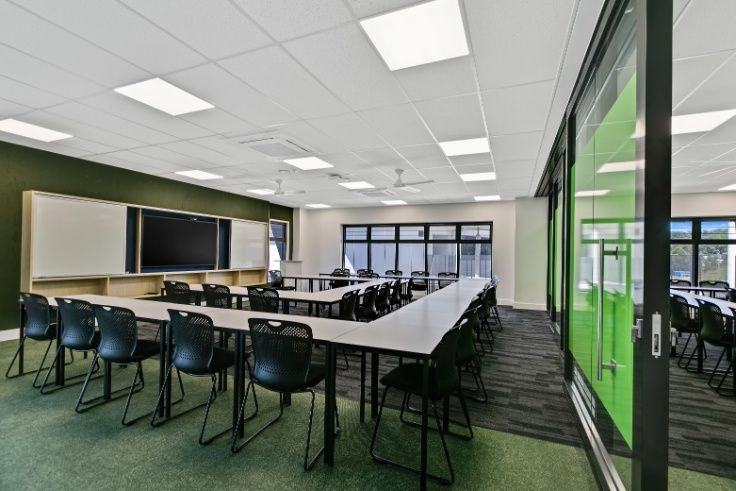 A Large Classroom With Tables and Chairs and a Television on the Wall — Architectural Glass Solutions QLD in Cooroy, QLD