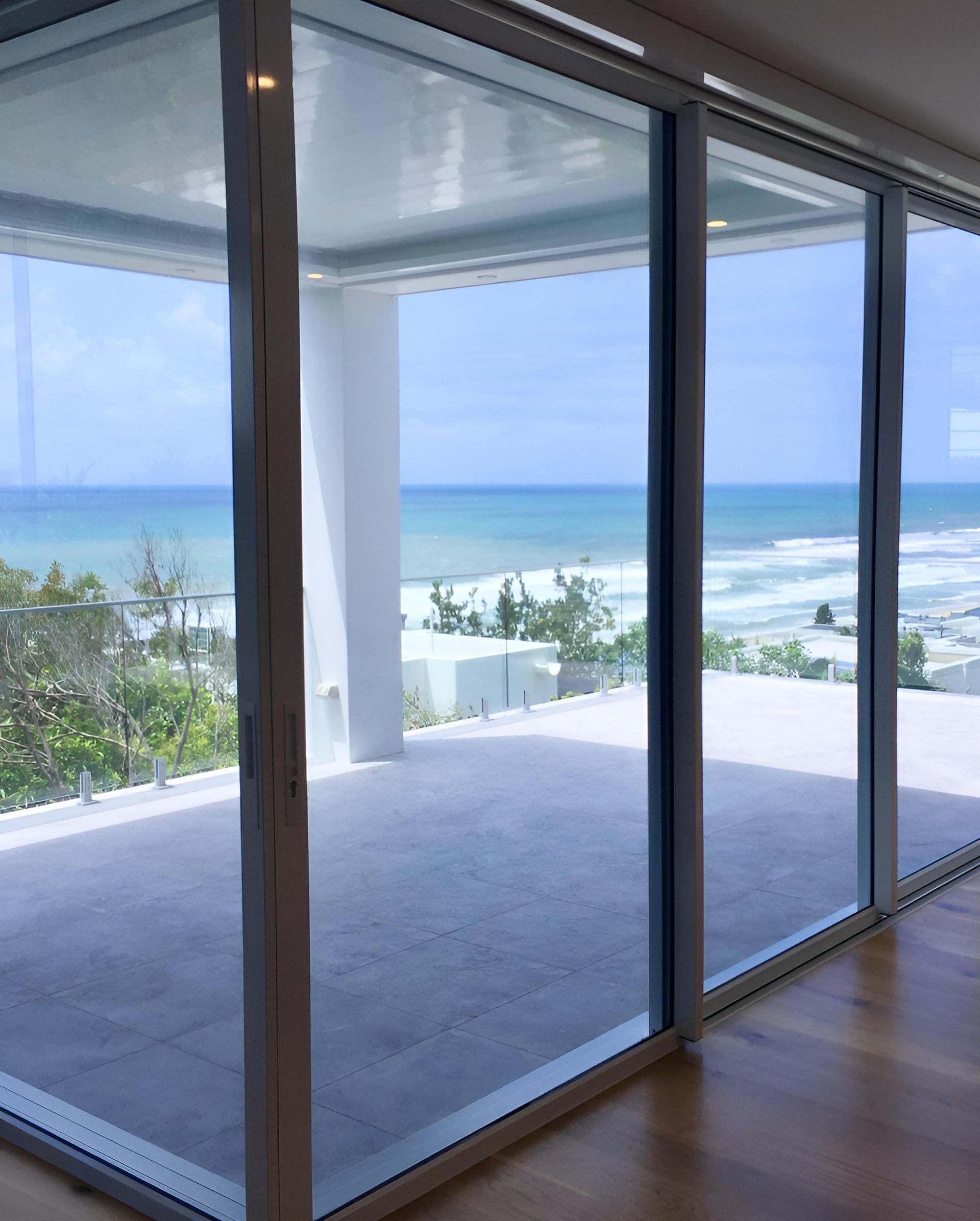 Sliding Glass Doors With Wood Floors and a Concrete Balcony — Architectural Glass Solutions QLD in Cooroy, QLD