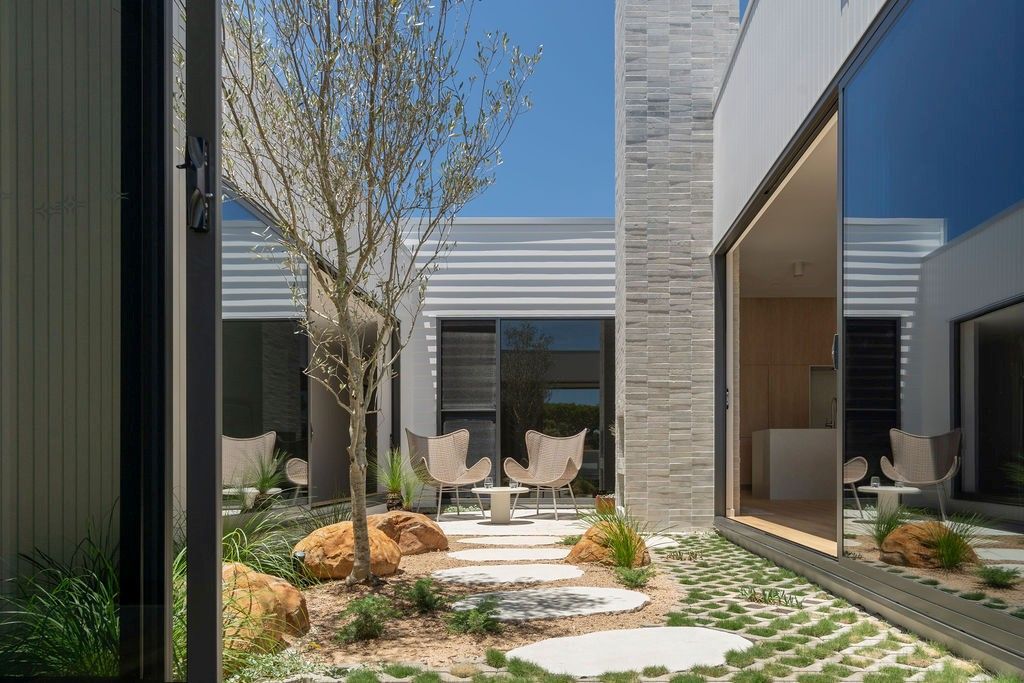 Courtyard with a tree, stone path, and seating between modern buildings — Architectural Glass Solutions QLD in Cooroy, QLD