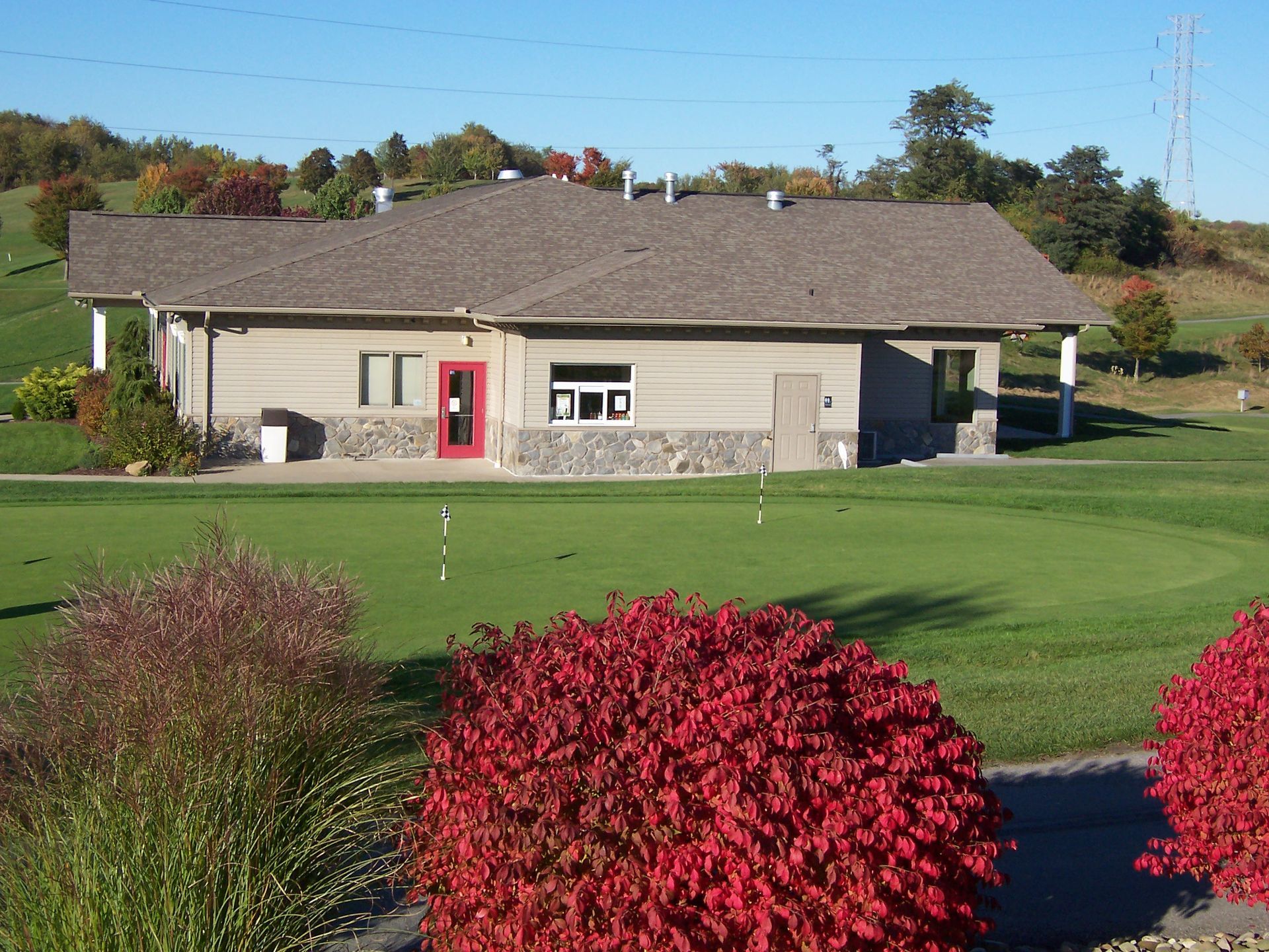 Golf course clubhouse with red door and colorful fall foliage.