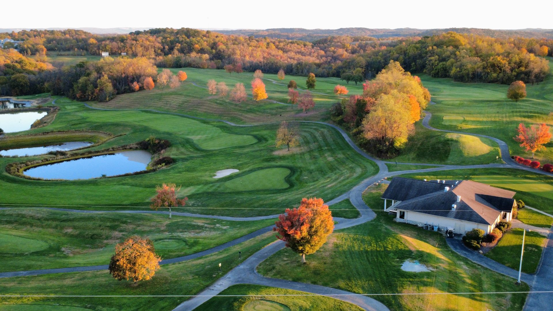 Golf course with vibrant fall foliage and a clubhouse.