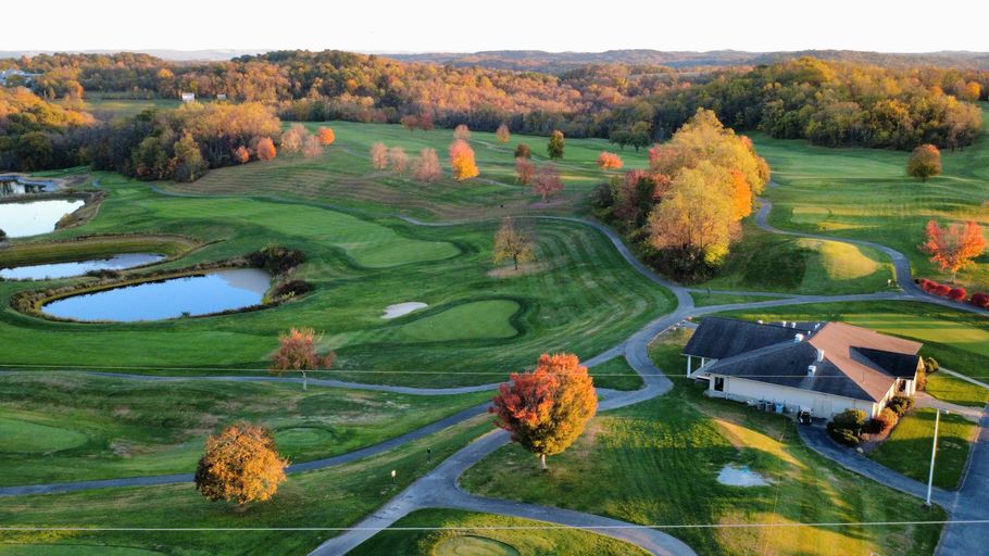 Golf course with vibrant fall foliage and a clubhouse.