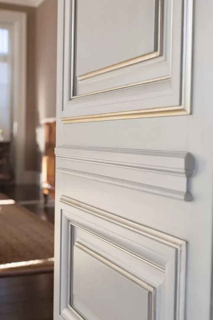 A close up of a white door with gold trim in a room.