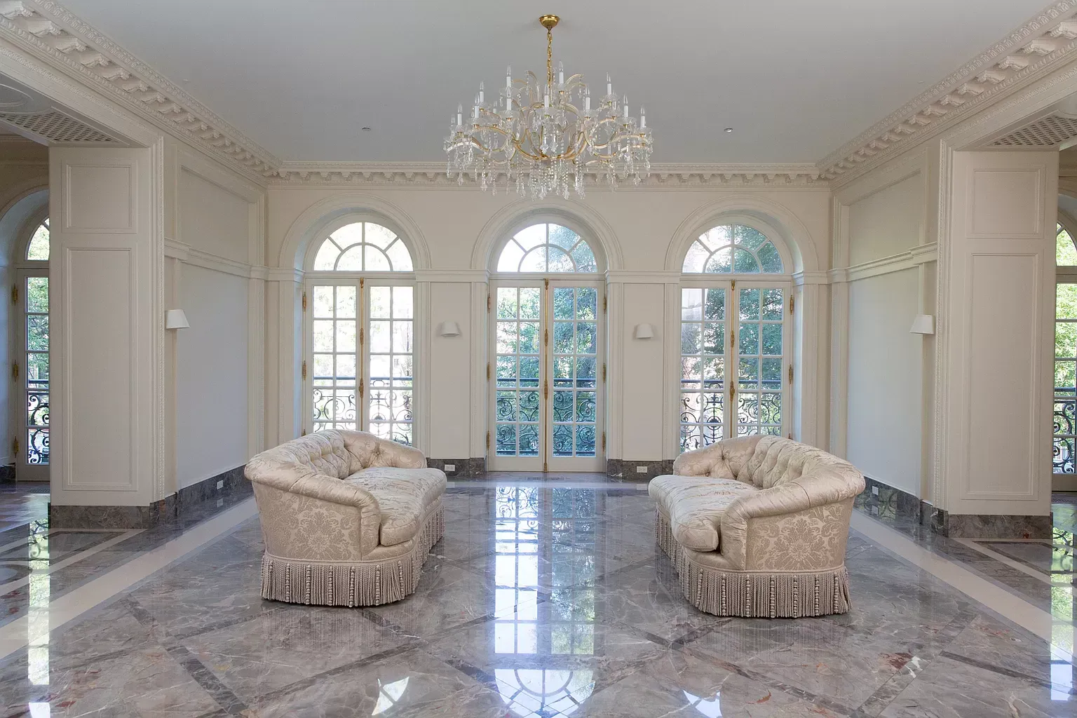 An empty living room with two couches and a chandelier.