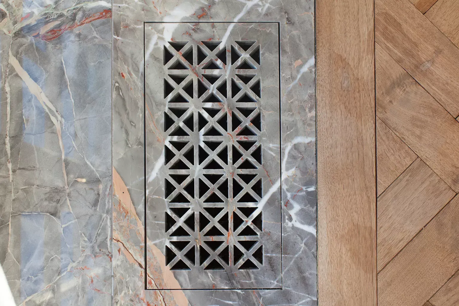 A marble wall with a metal grille on it