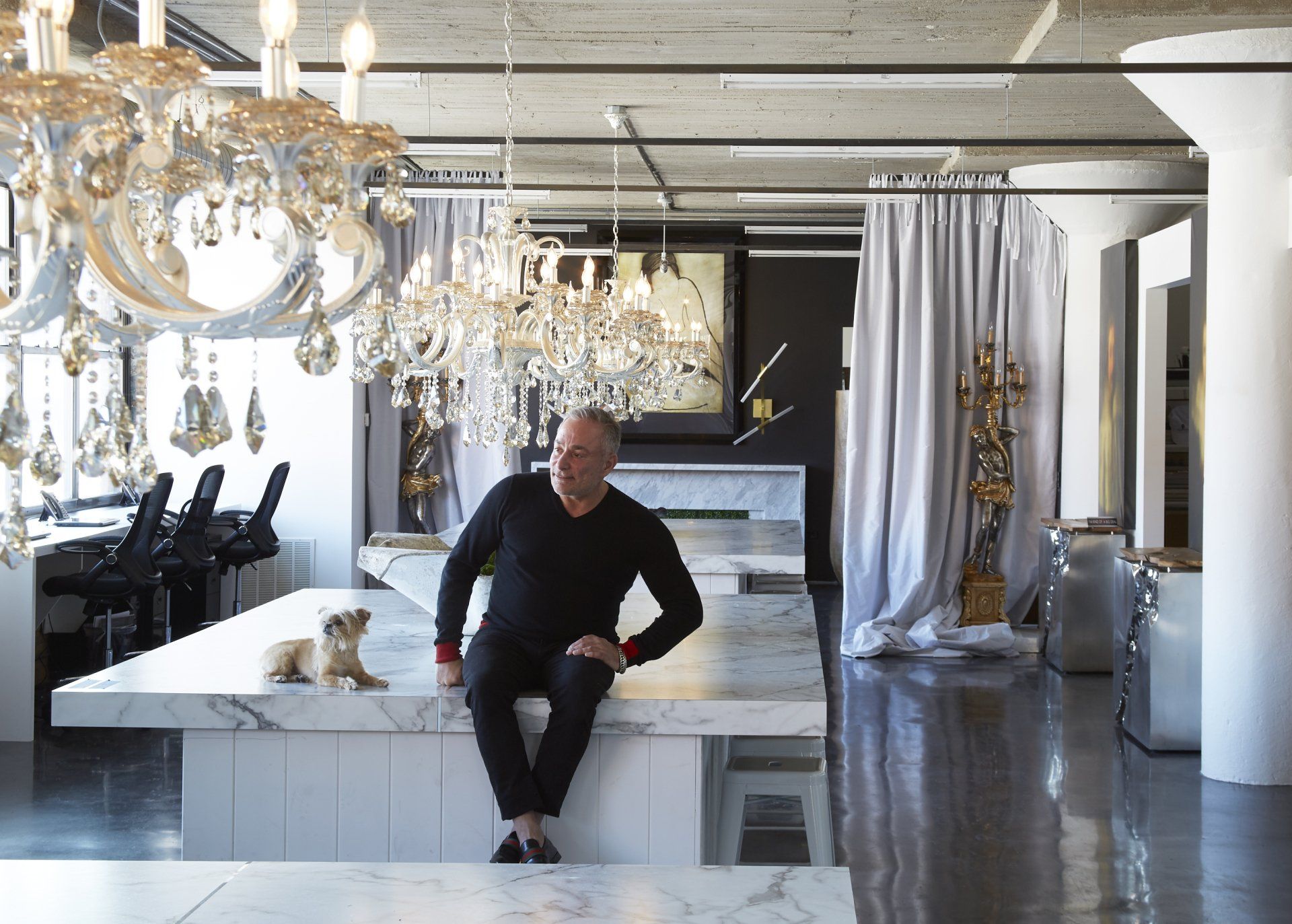 A man is sitting on a table in a room with lots of chandeliers