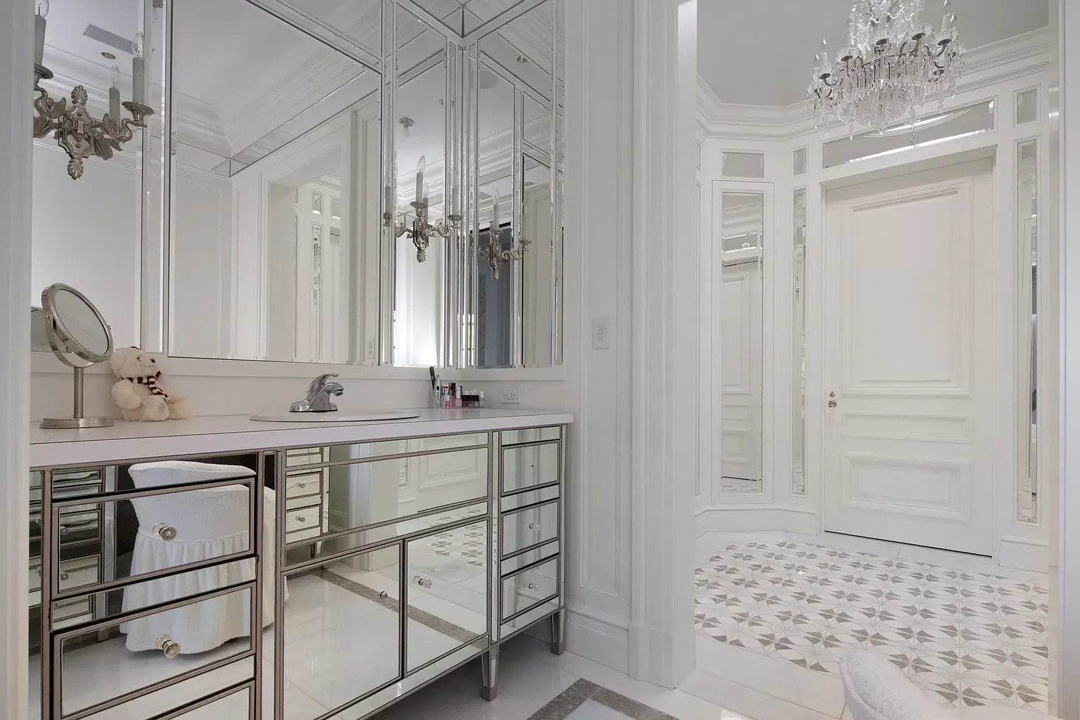 A bathroom with two sinks , a mirror and a chandelier.