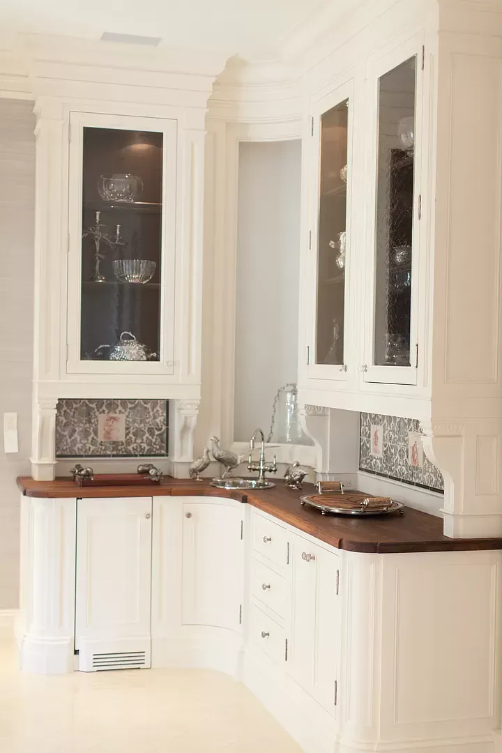 A kitchen with white cabinets and a wooden counter top.