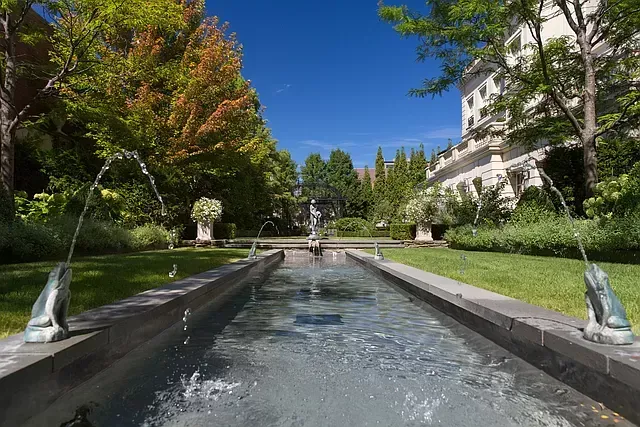 A fountain in a garden with a building in the background.