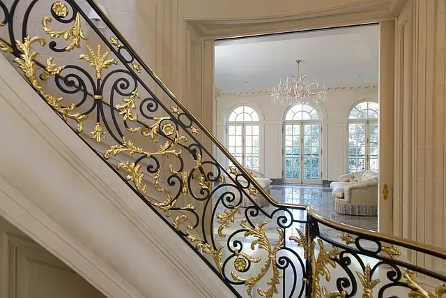 A staircase with a wrought iron railing leading up to a living room.