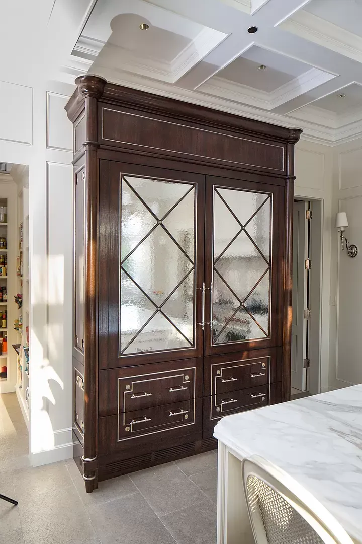 A large wooden cabinet with mirrored doors in a kitchen.