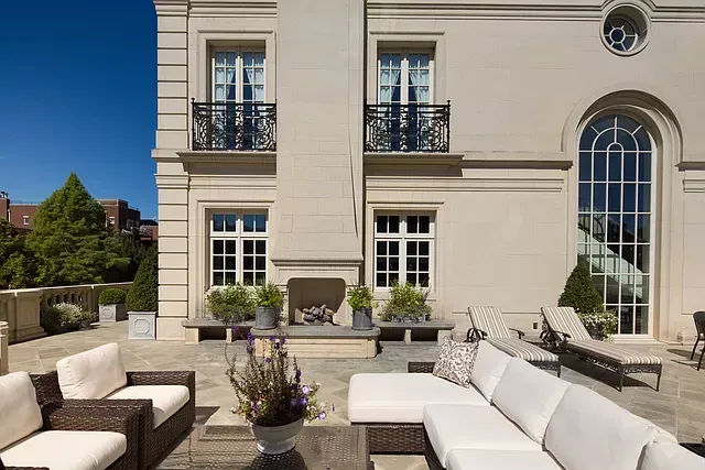 A large house with a patio area with a couch and chairs