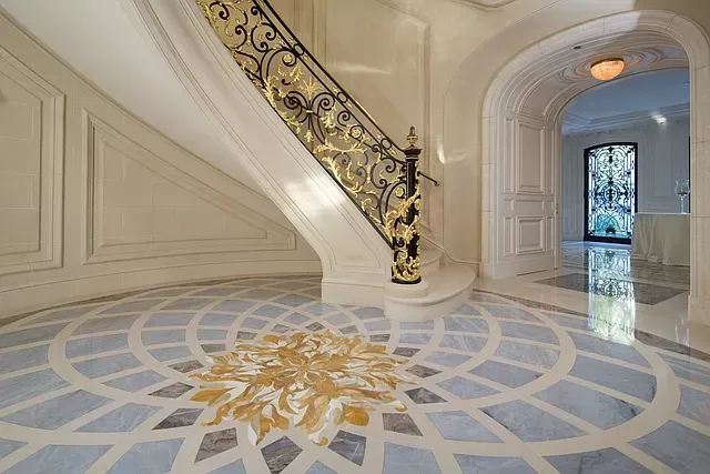 A staircase with a circular pattern on the floor and a wrought iron railing.