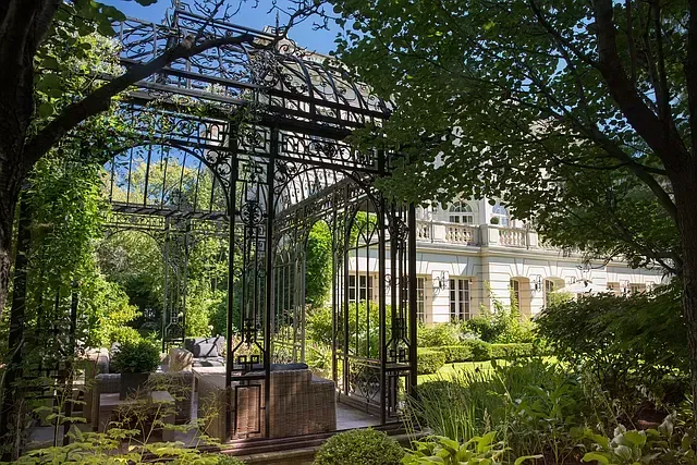 There is a gazebo in the middle of a garden surrounded by trees.