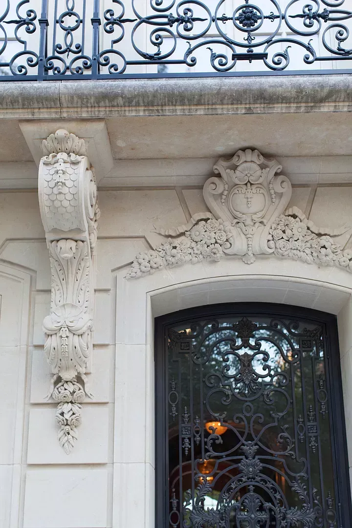The front of a building with a wrought iron balcony and door.