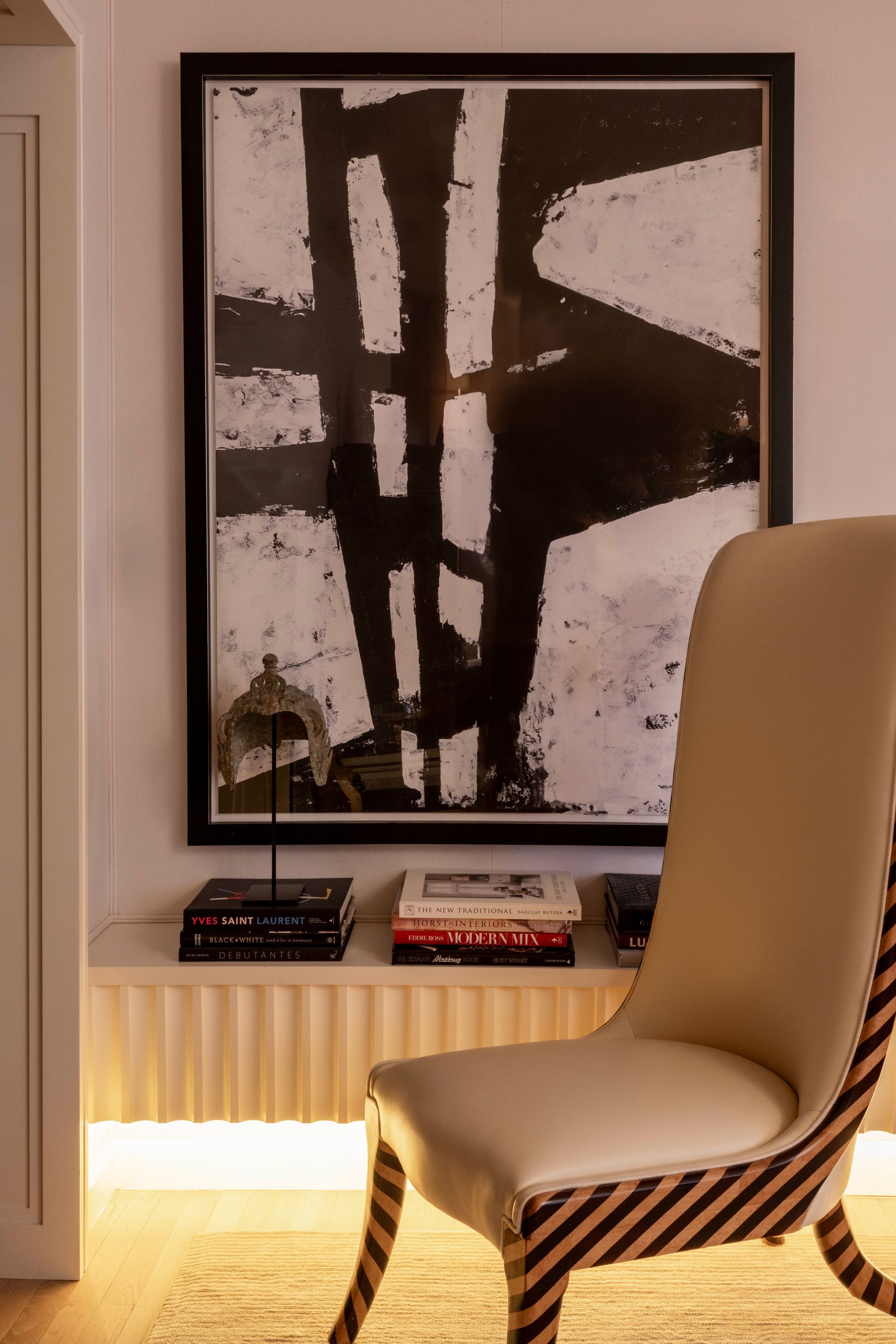 A chair is sitting in front of a painting on the wall.