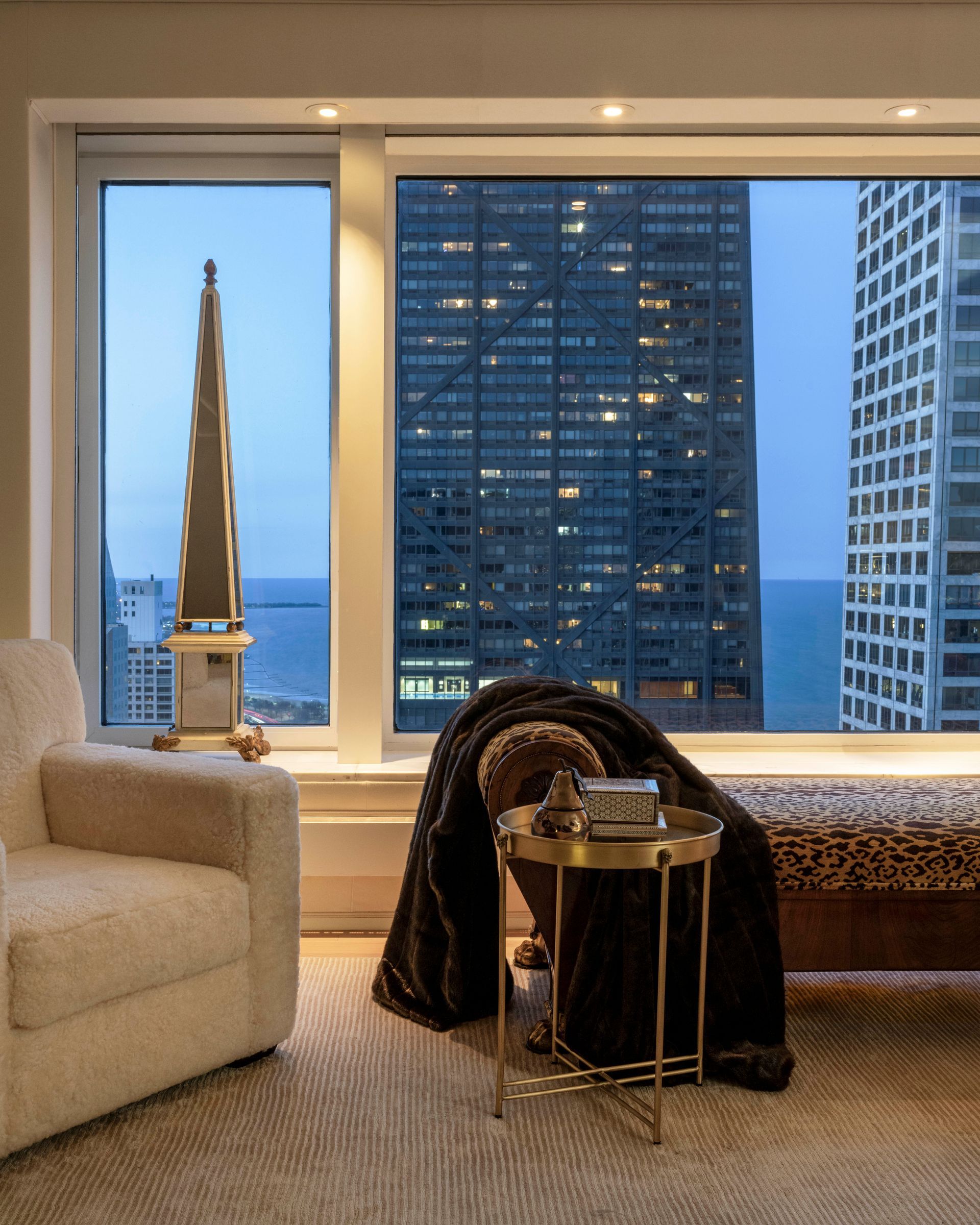 A living room with a chair and a table in front of a large window.