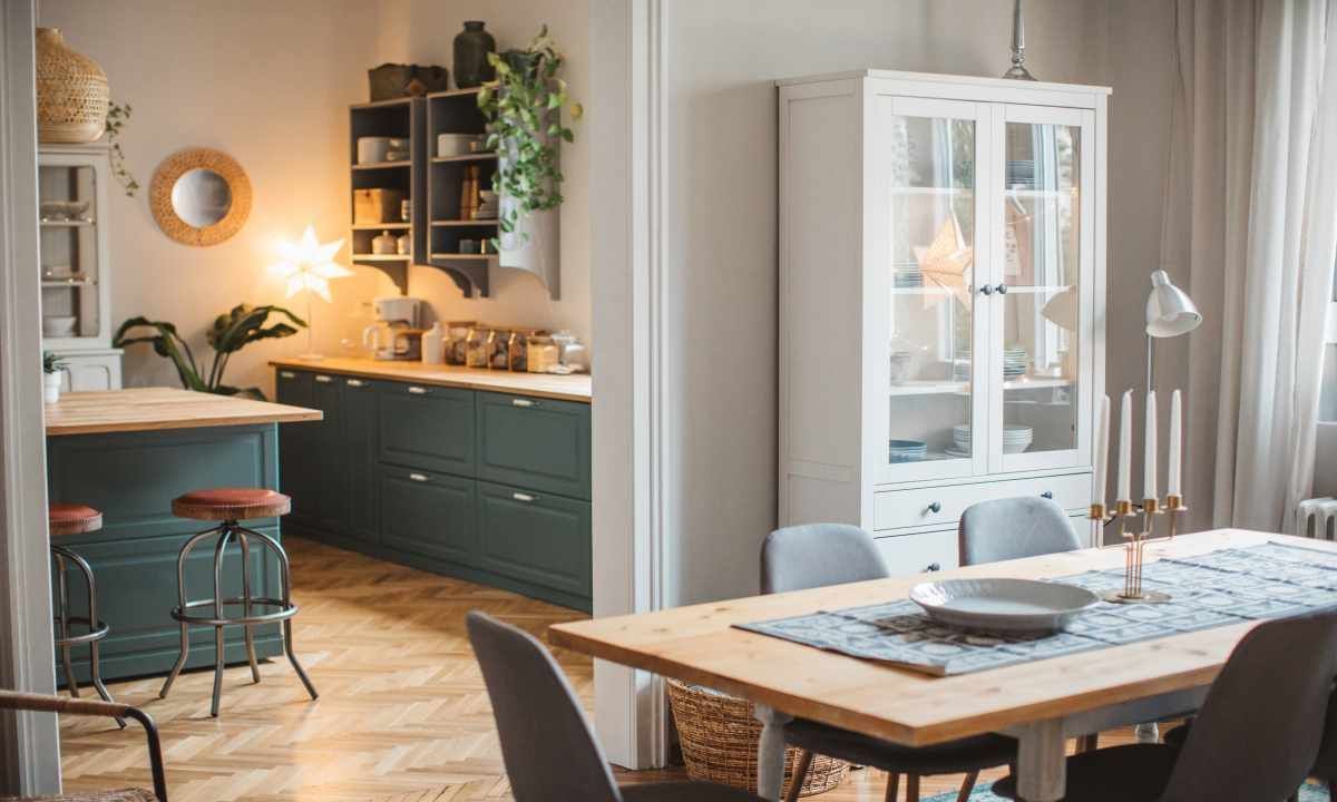 A dining room with a table and chairs and a kitchen in the background.