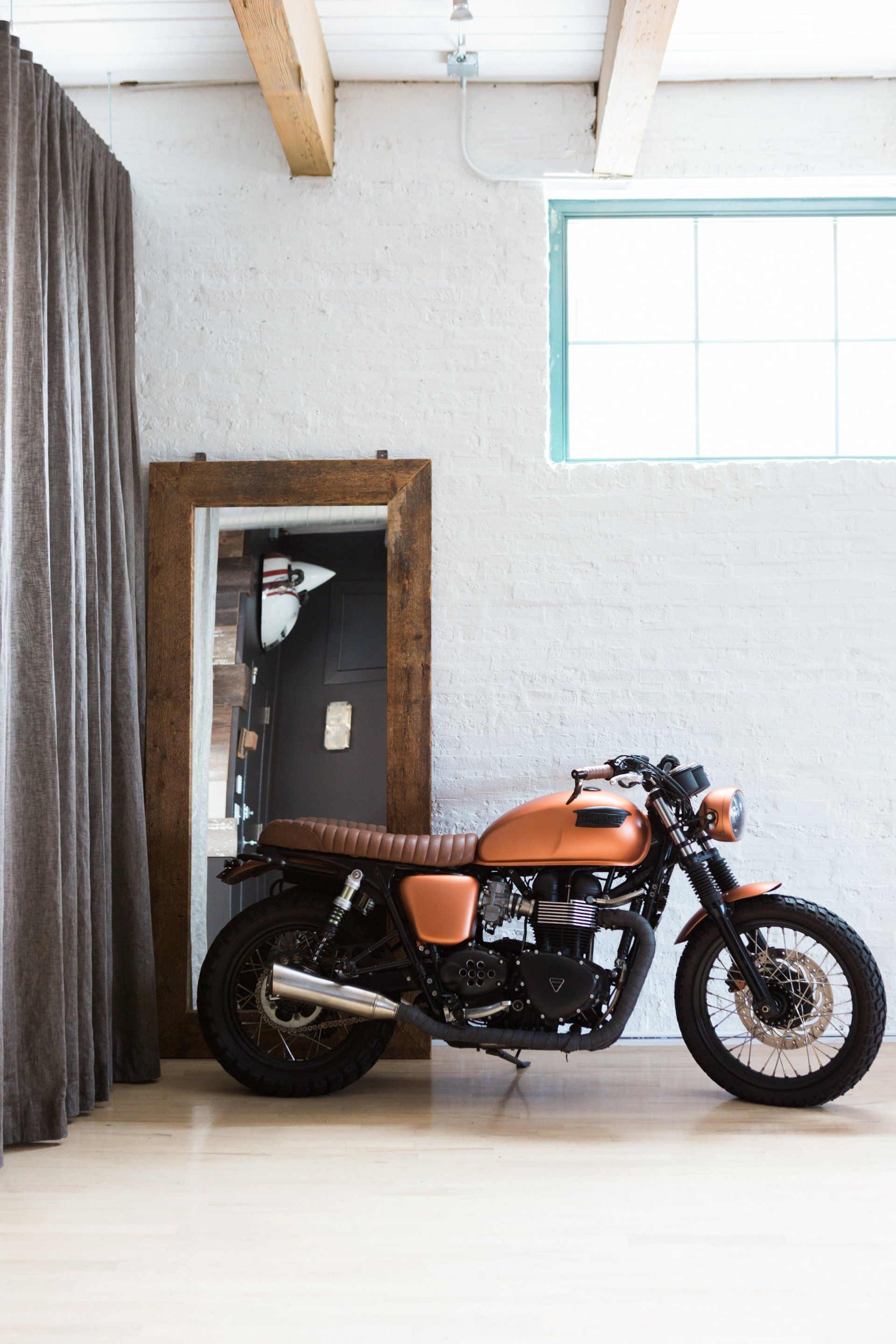 A motorcycle is parked in a room next to a window.