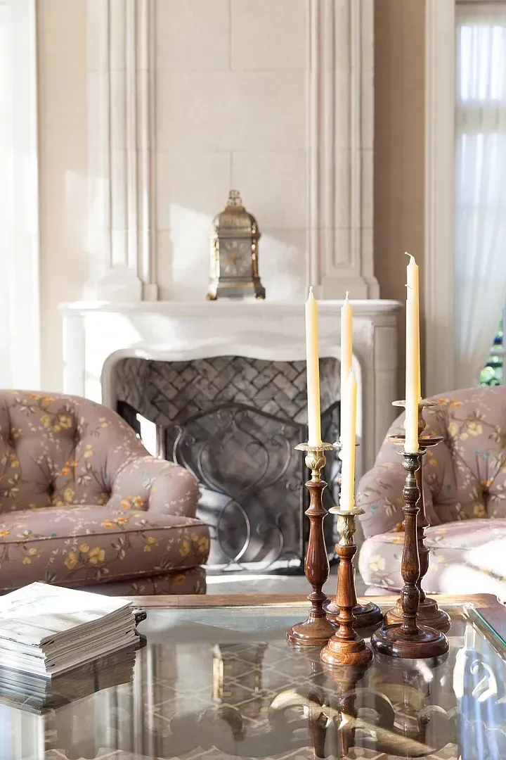A living room with a fireplace and candles on the table.