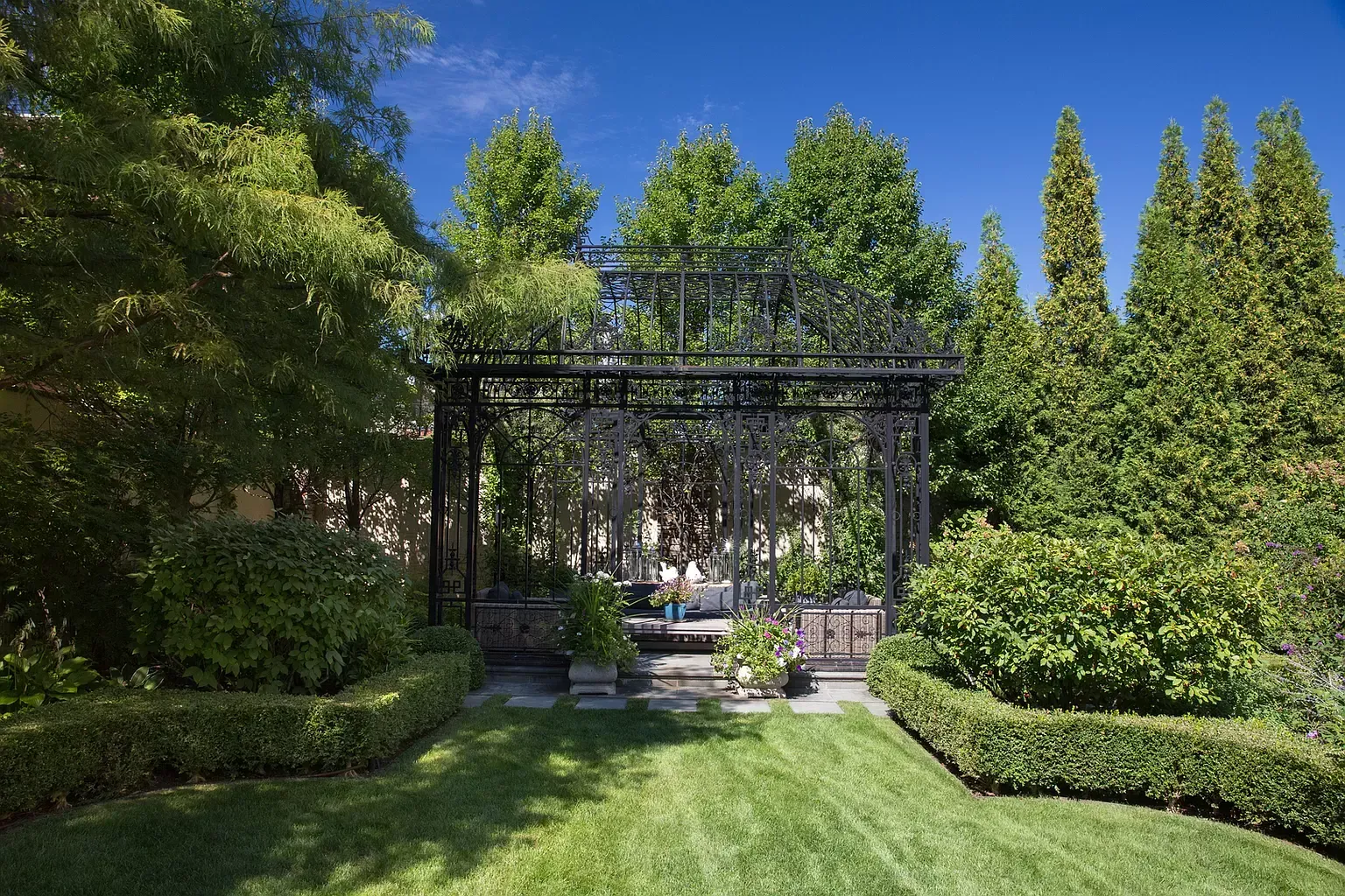 A lush green garden with trees and bushes and a gate