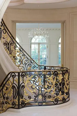 A wrought iron staircase with a gold railing in a house.