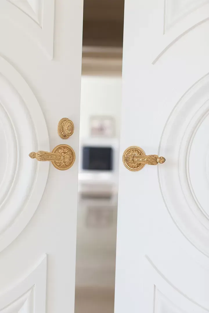 A close up of a white door with gold handles.
