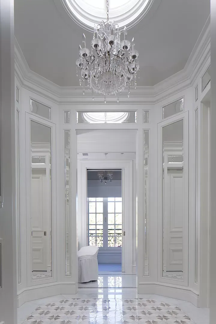 A white hallway with a chandelier hanging from the ceiling.