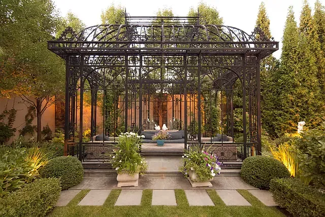 A gazebo in the middle of a garden surrounded by trees