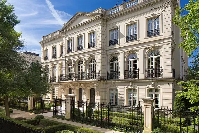 A large white building with a wrought iron fence around it.