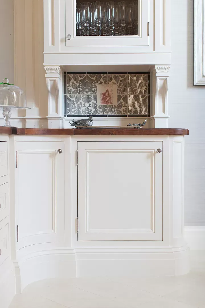 A kitchen with white cabinets and a wooden counter top.