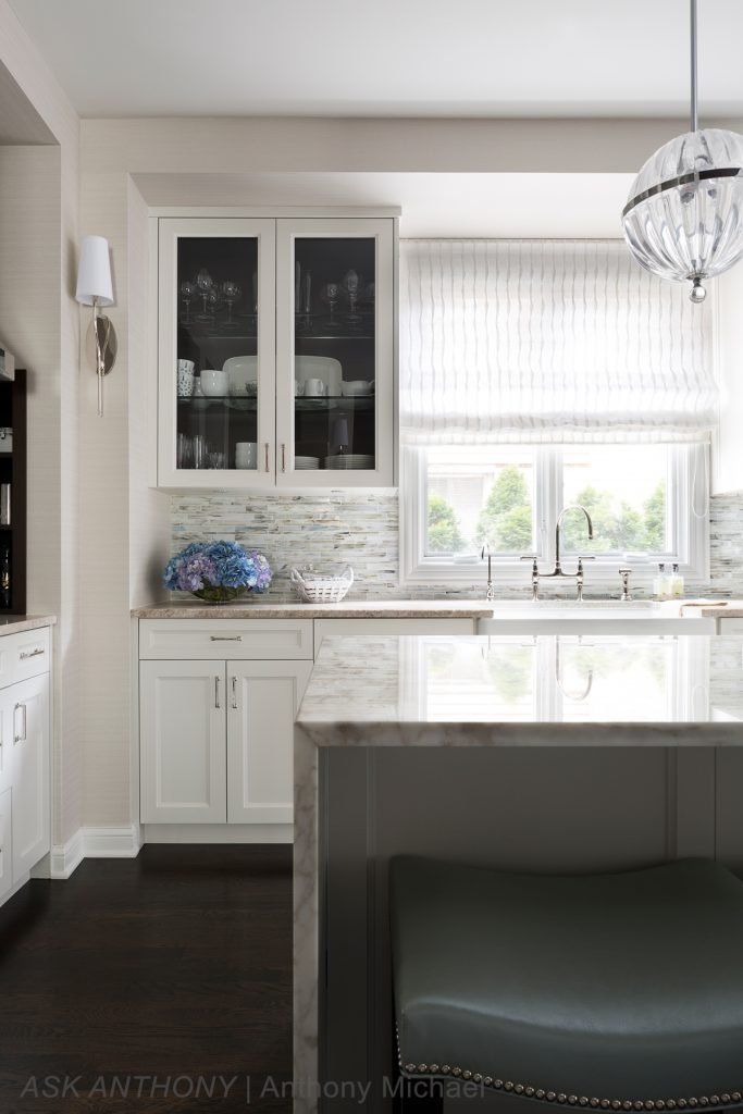 A kitchen with white cabinets , a sink , and a large island.