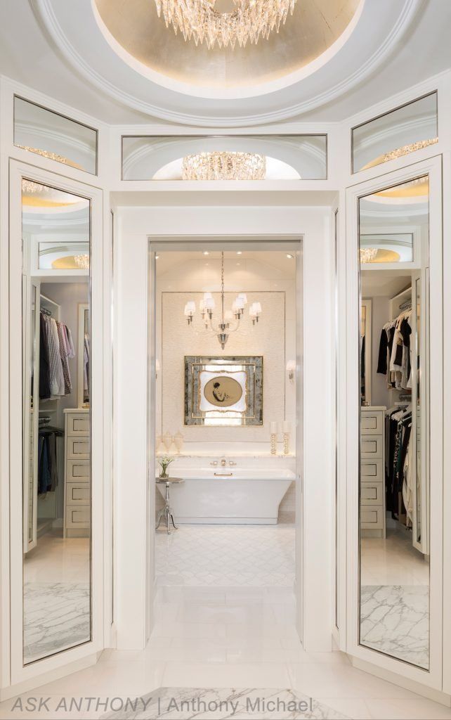A walk in closet with a bathtub and a chandelier.