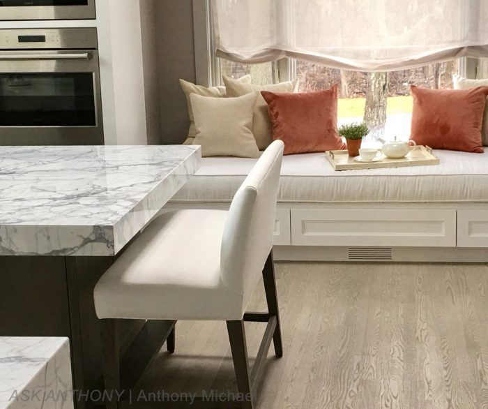 A kitchen with a marble counter top and a window seat