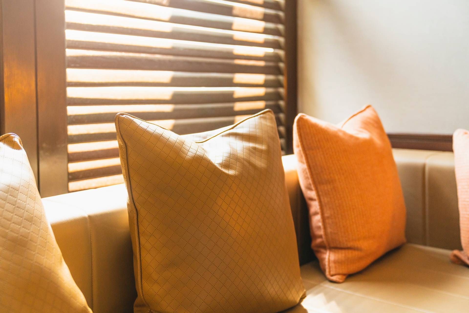 Image of a sunroom with shutters that are custom-made, cozy window seating, and throw pillows near T