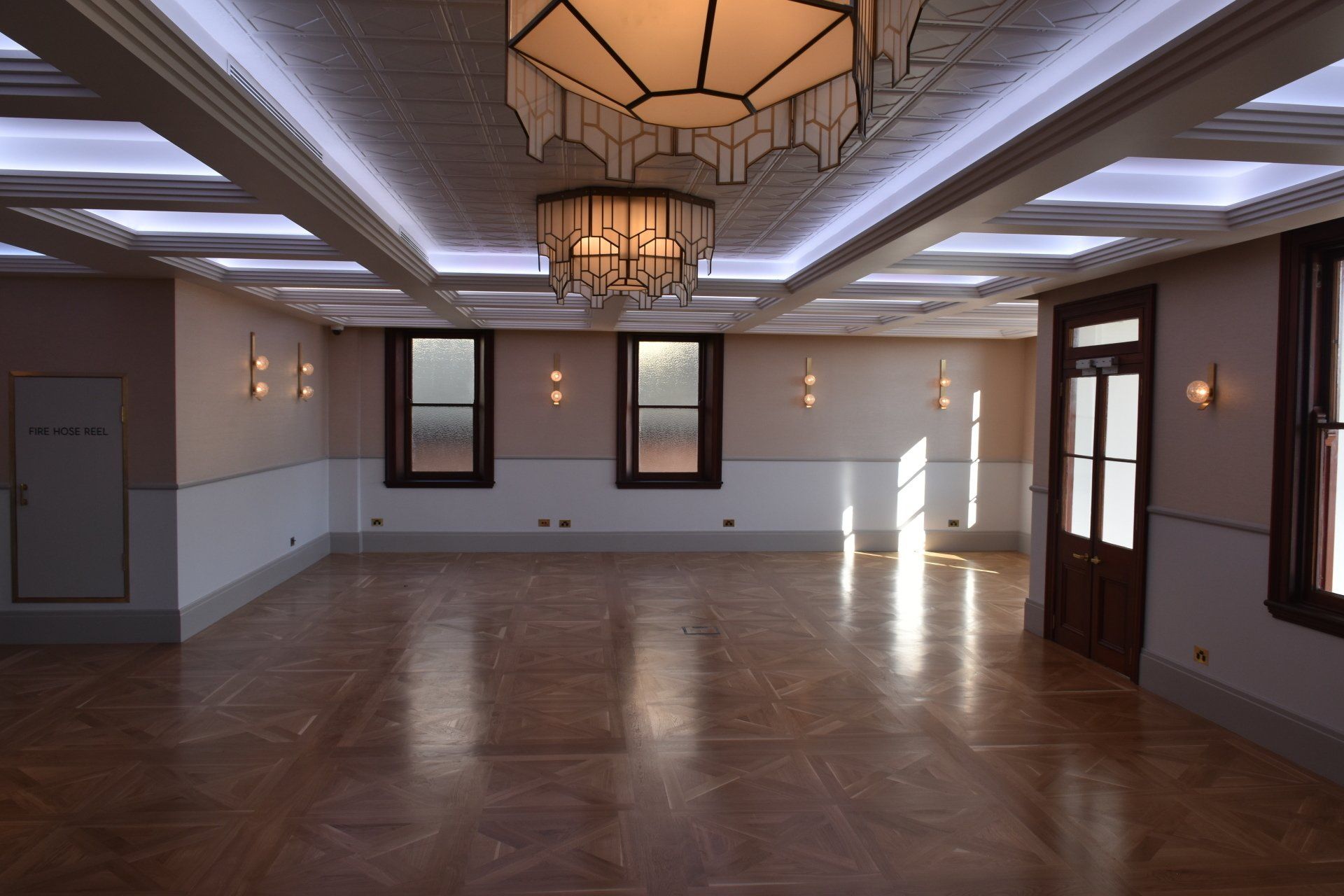 a large empty room with hardwood floors and a chandelier