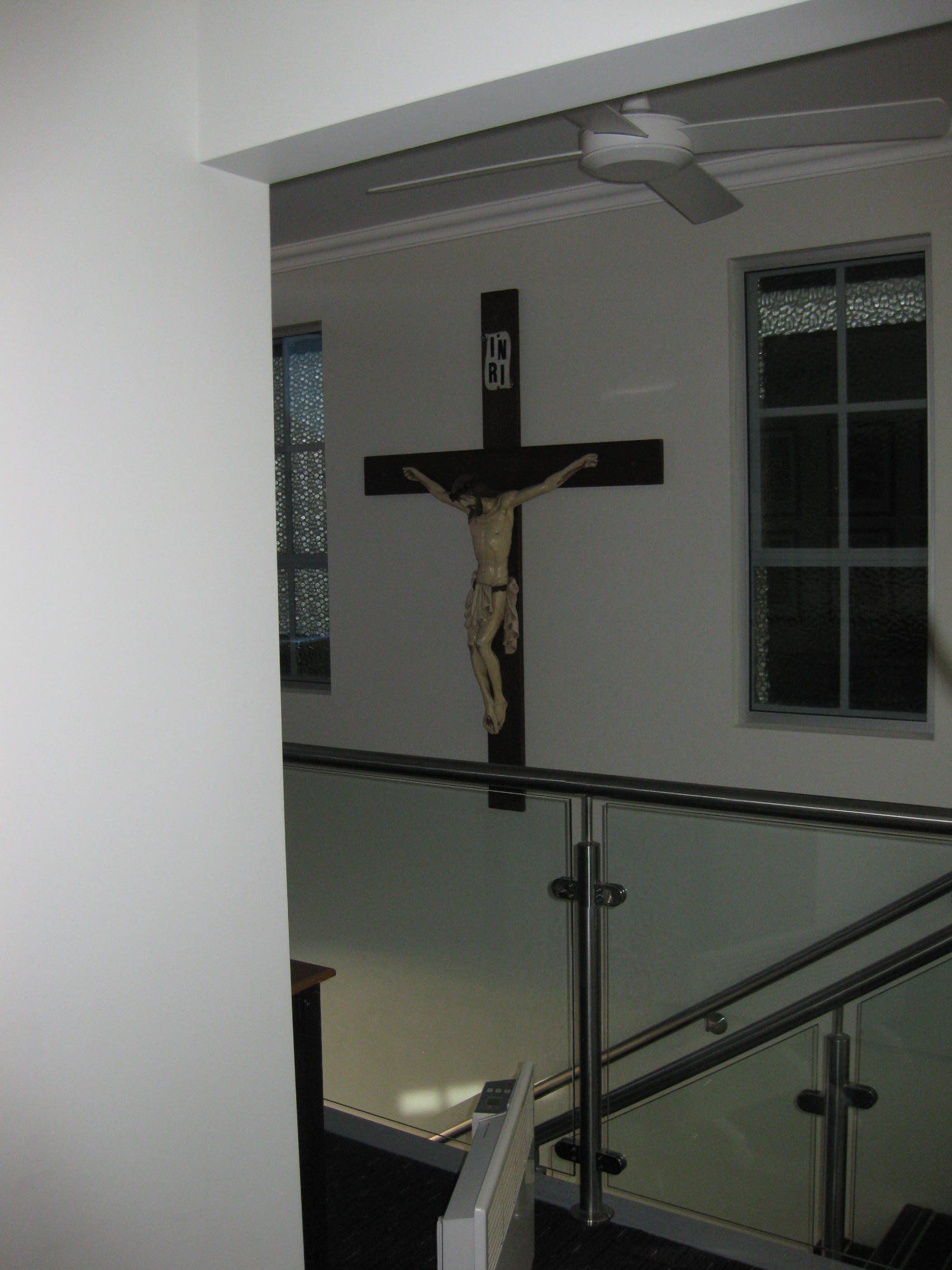a cross sitting on a wall next to staircase
