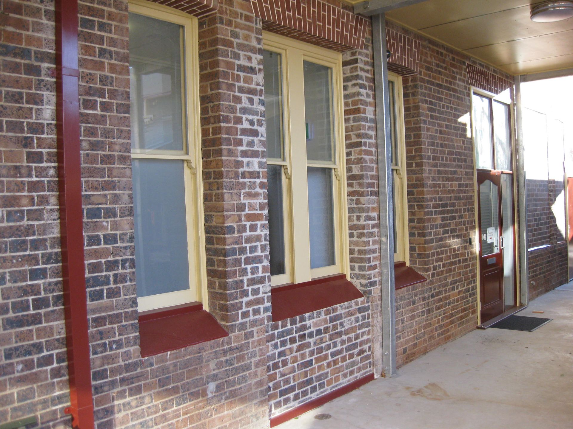 a brick building with three windows and a door with red painted trims