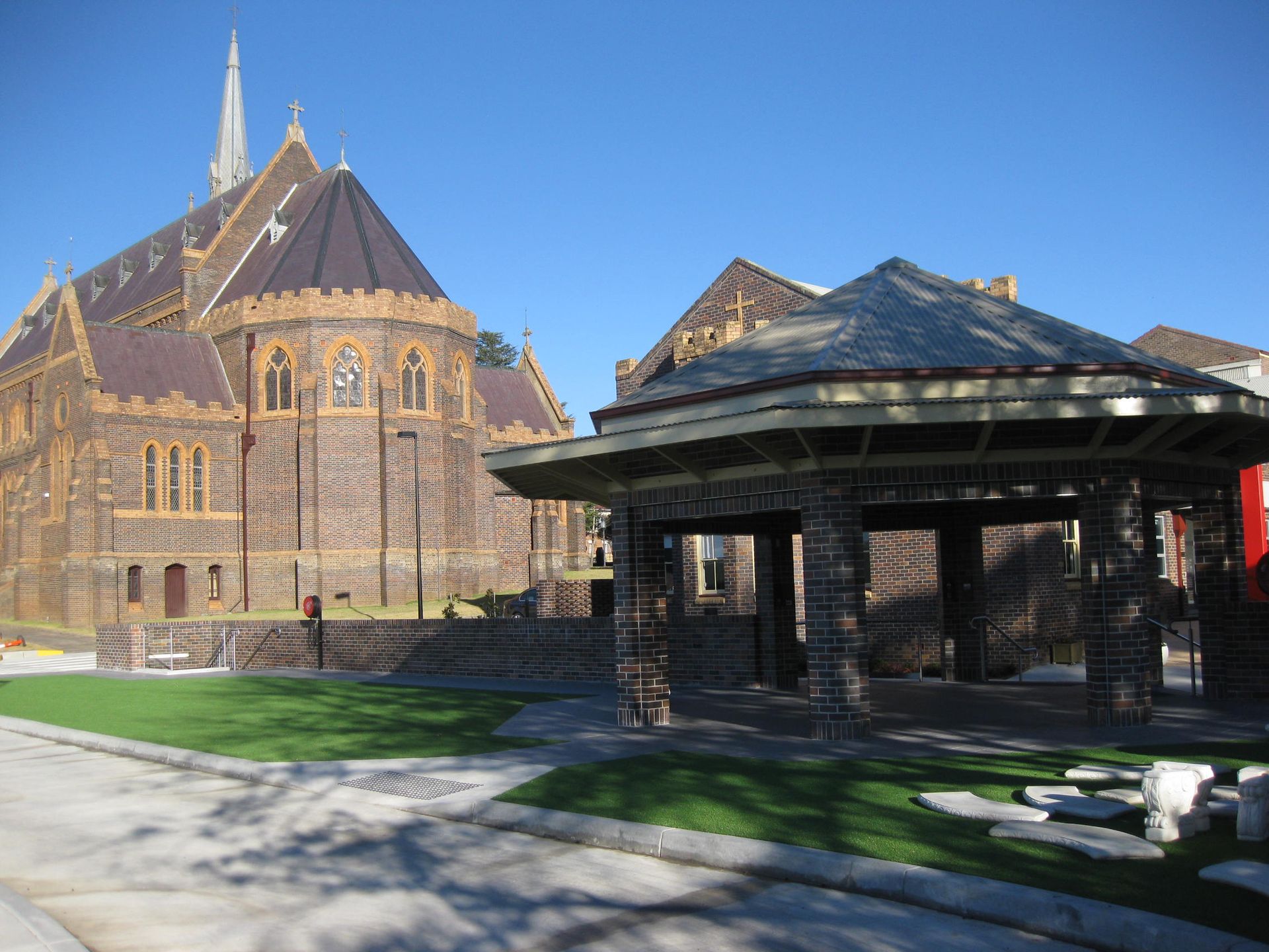 exterior of catholic cathedral precinct with a steeple and a gazebo in front of it