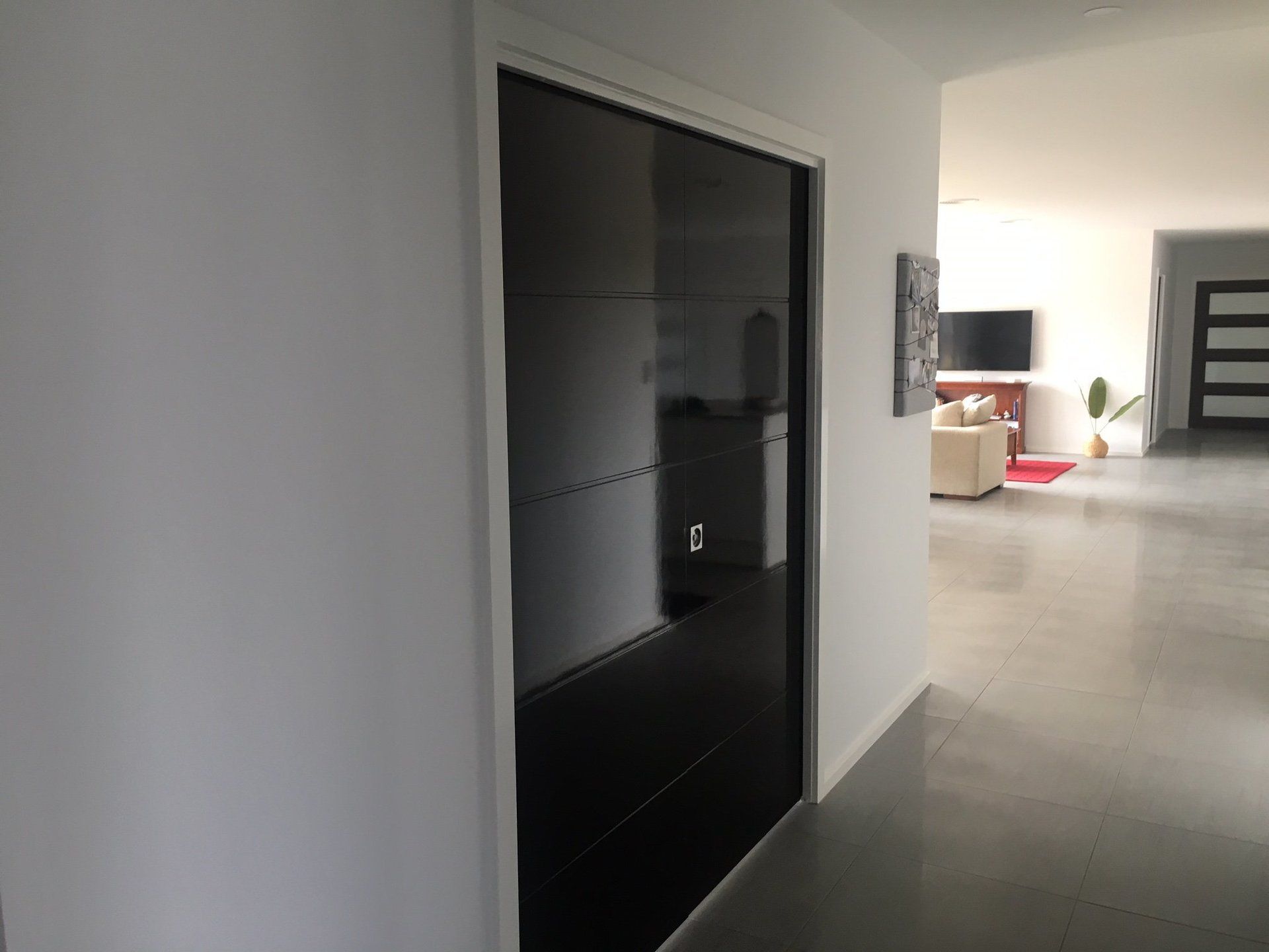 a hallway with a black door leading to a living room