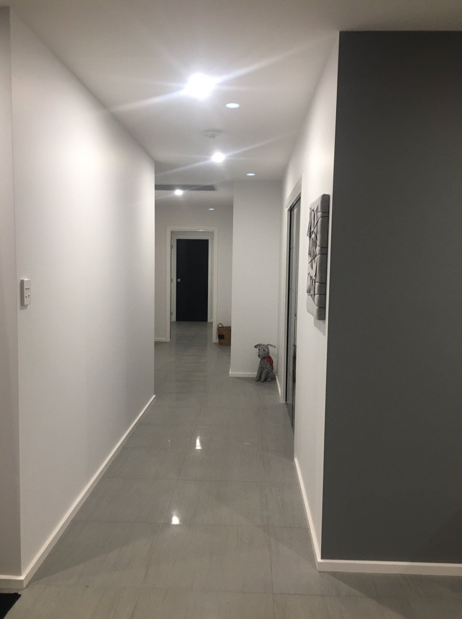 a long hallway with white walls and a gray feature wall.