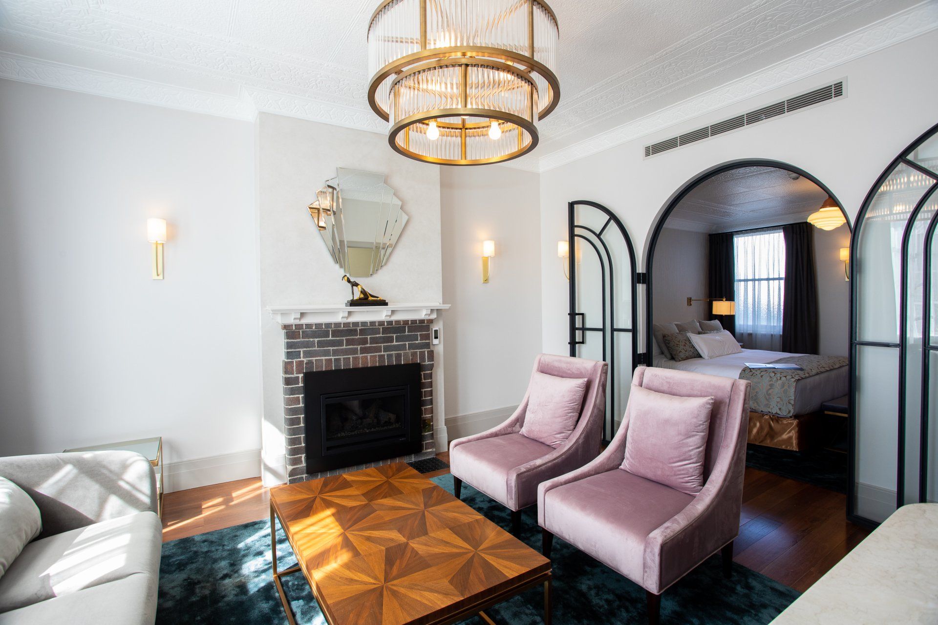 a room at tattersalls hotel with a fireplace, chairs, a couch and a chandelier.