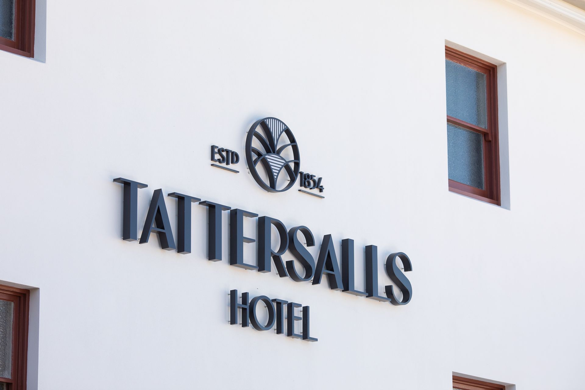 Front of tattersalls hotel with large logo on white wall