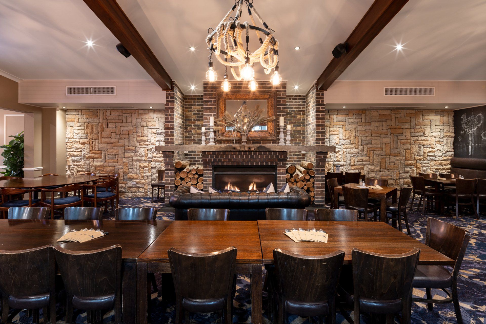 a dining room with tables and chairs and a fireplace at whitebull hotel in armidale 