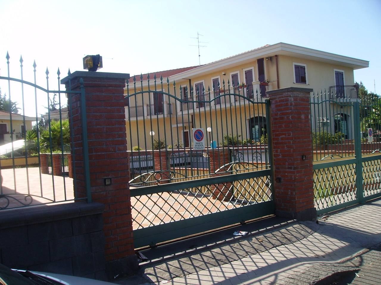 Un cancello scorrevole è aperto su una grande casa