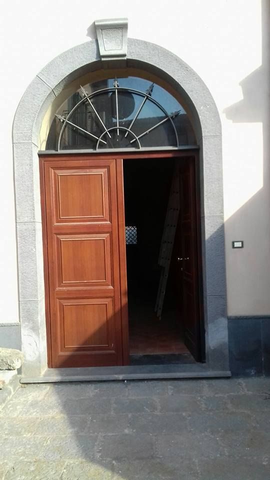 Una porta di legno con un arco in pietra si apre su una stanza.