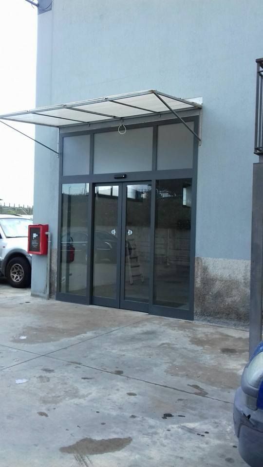 Un'auto è parcheggiata davanti a un edificio con una porta scorrevole in vetro.