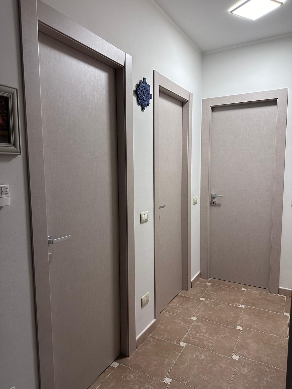 Un corridoio con tante porte e un quadro sul muro