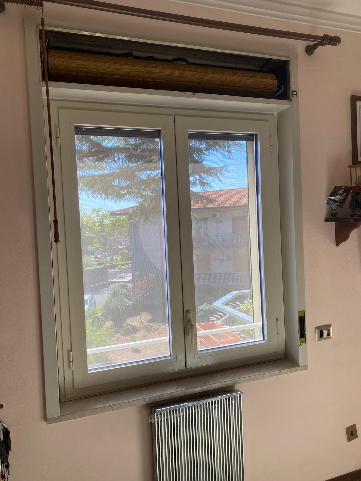 Una stanza con una finestra e un termosifone.