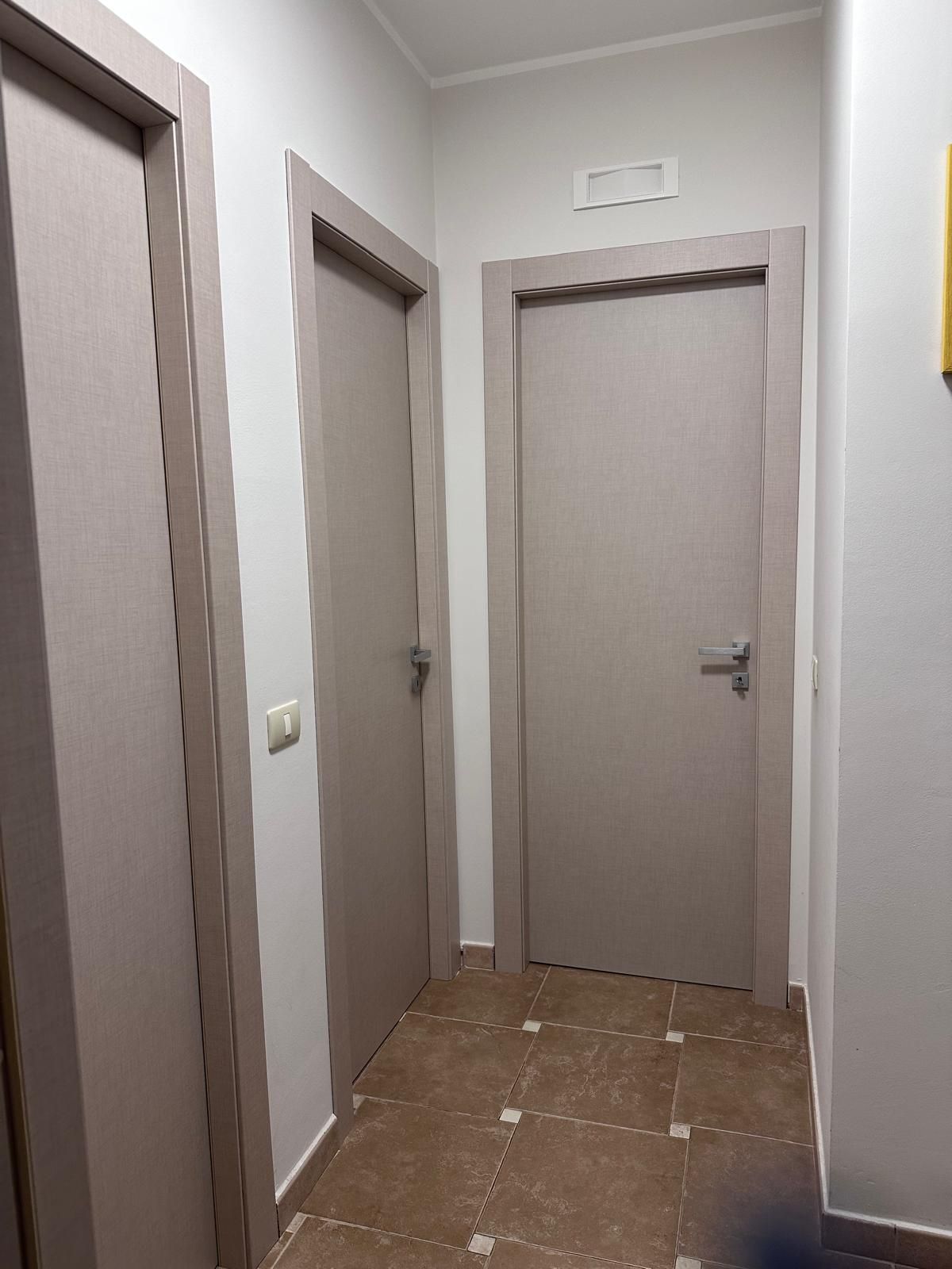 Un corridoio con due porte e un pavimento piastrellato.